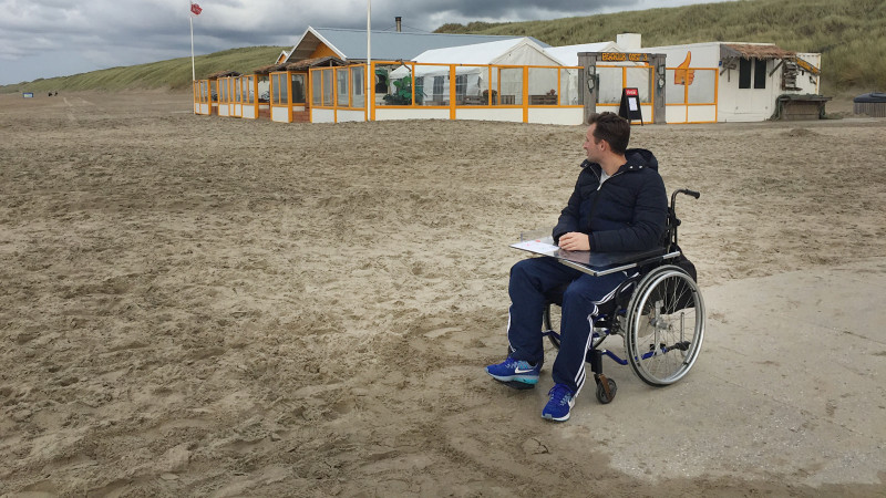 Jurjen met zijn rolstoel op het strand