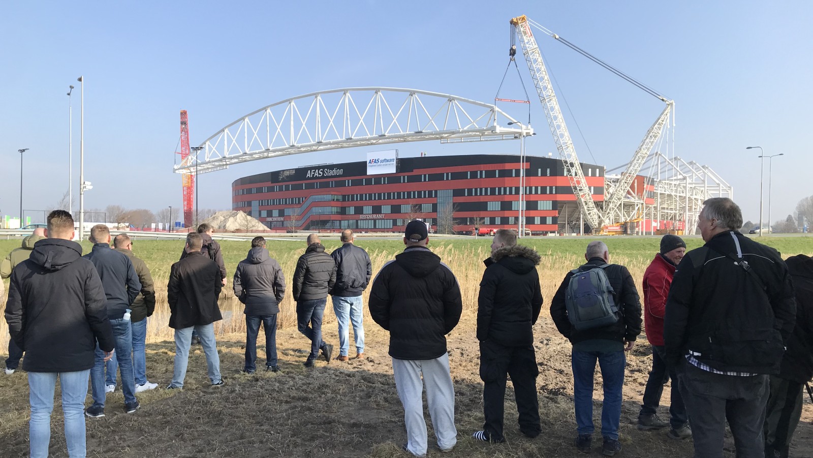 Toeschouwers kijken hoe het nieuwe dak op het AZ-stadion wordt geplaatst