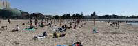 Een groep mensen op een strand vlakbij een gebouw.