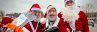 Drie mannen verkleed als kerstman poseren voor een foto.