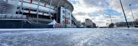 Een besneeuwde weg voor een stadion.