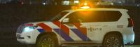 Een politieauto rijdt 's nachts over de weg.