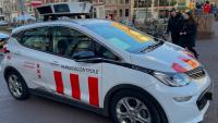 Een witte auto uitgerust met scanners op het dak is gemarkeerd met "parkeercontrole" en het embleem van de stad Amsterdam, wat aangeeft dat deze wordt gebruikt voor parkeerhandhaving.