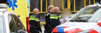 Politieagenten en een ambulance buiten een gebouw, gericht op een incident, met een politieauto en ambulance zichtbaar. Het gezicht van één persoon is om privacyredenen verborgen.