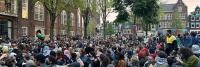 Een grote mensenmassa verzamelt zich op een stadsplein, omringd door historische gebouwen, mogelijk voor een publieksevenement of demonstratie.