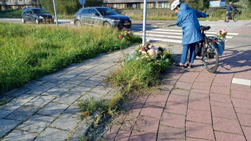 Een voorbijganger kijkt naar de bloemen op de plek van het ongeluk