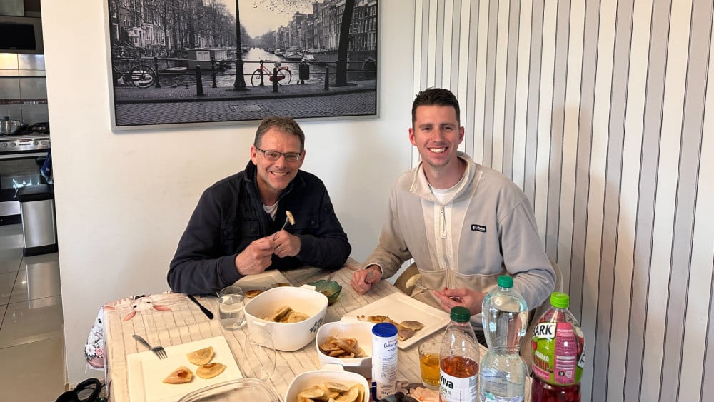 Op traditionele klapki een bordje pierogi eten bij een AZ-supporter in Polen