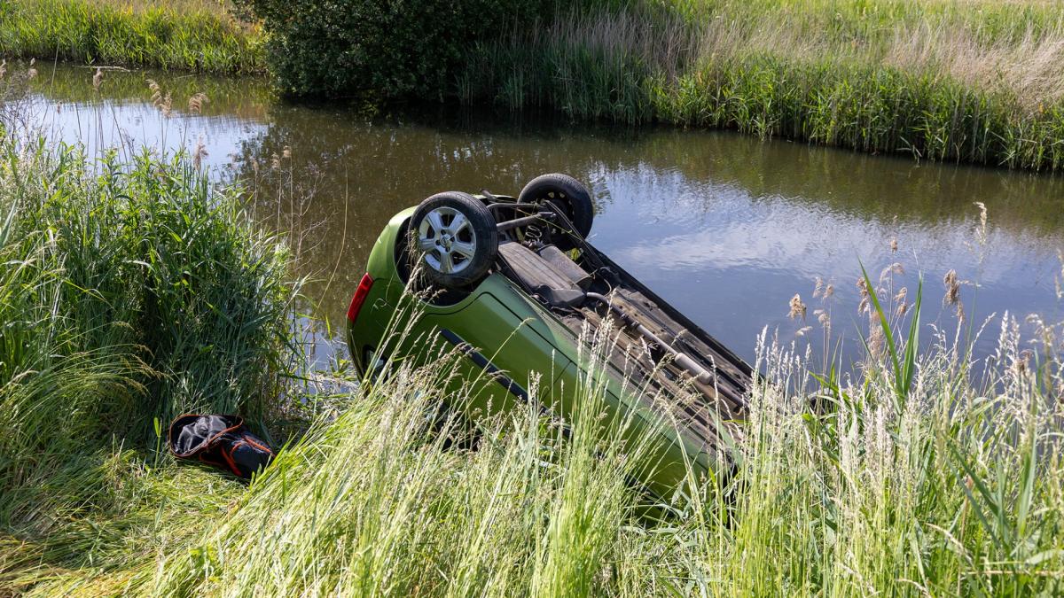 Auto belandt op z'n kop in het water, bestuurder klimt er zelf uit