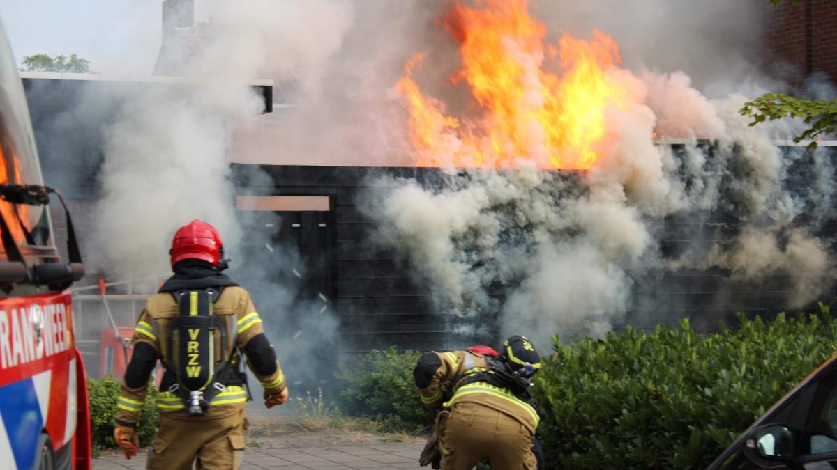 Brandweer blust vlammen van brandend schuurtje bij woning